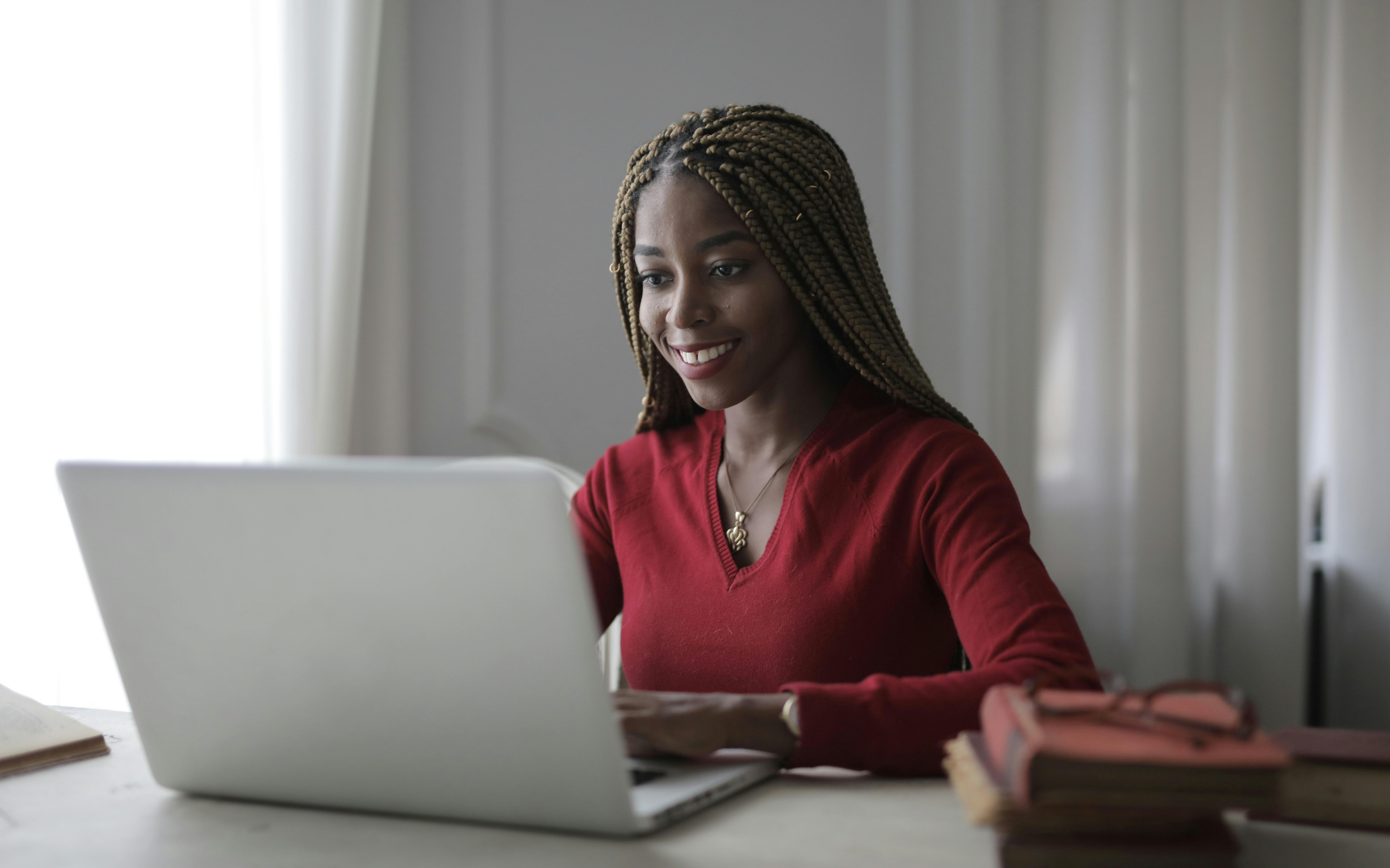 Woman smiling while working on laptop at desk
